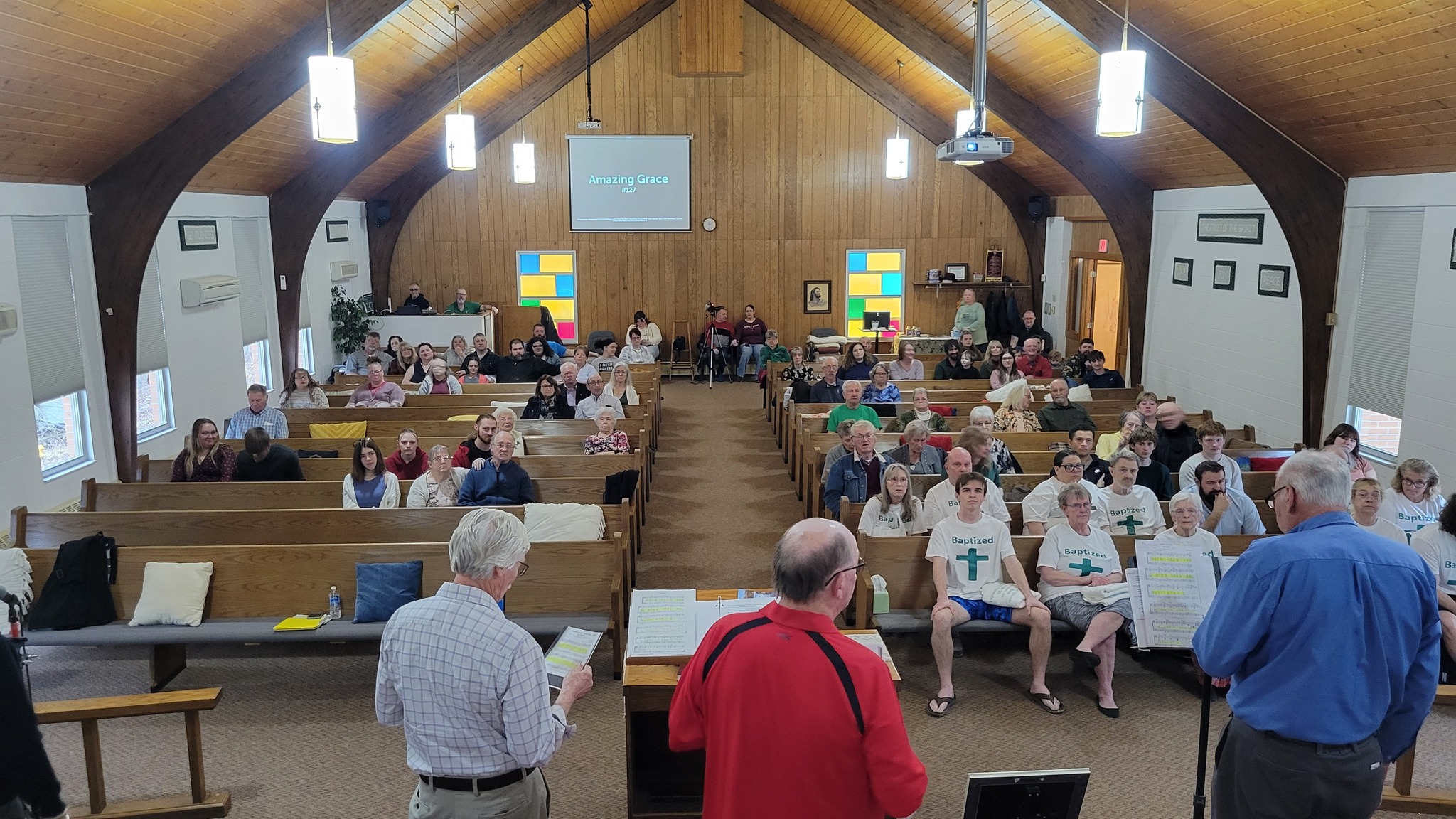 Full church sanctuary during Sunday worship service with Amazing Grace on screen
